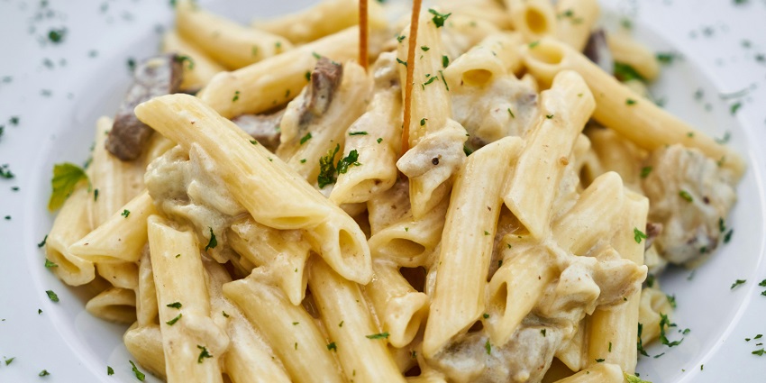White sauce pasta served at Salt & Pepper Bistro on a ceramic plate.
