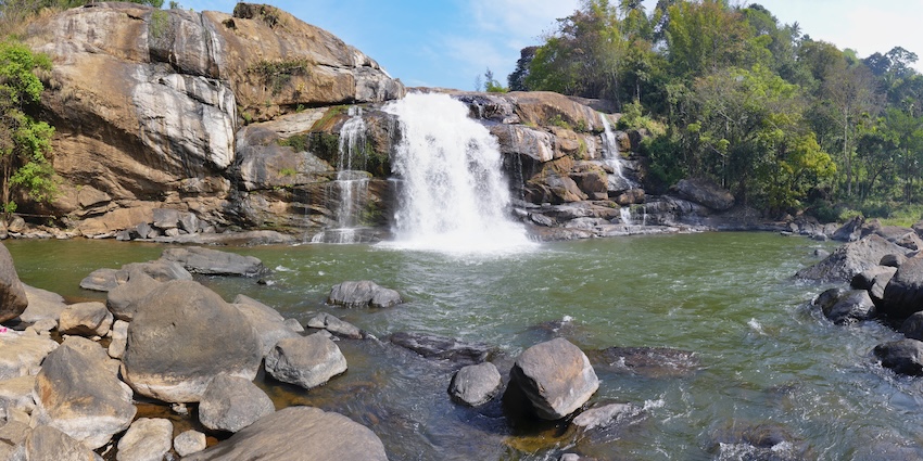 Whitewater rushing over rocks, surrounded by thick green foliage, one of the best among Tripura waterfalls.