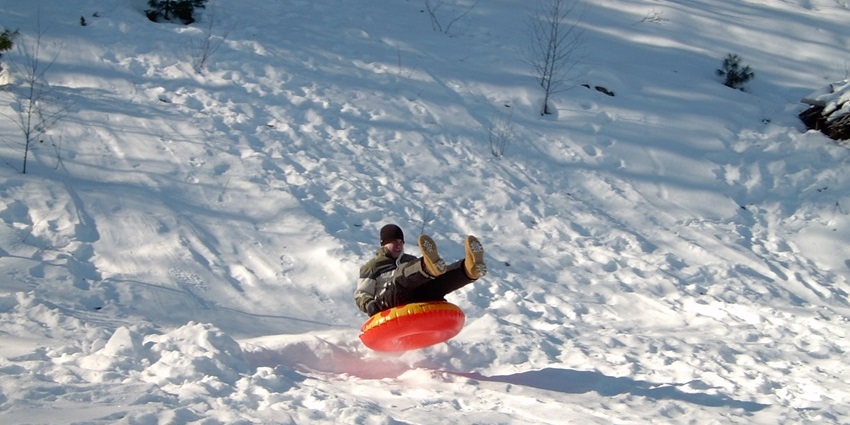 Families having fun sledding through powdery snowfall in Himachal Pradesh.
