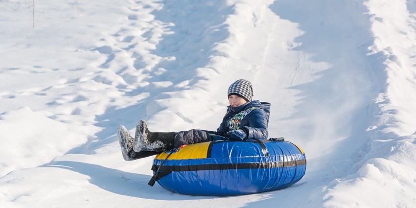 Children enjoying sledding on snow-covered slopes during winter in a hilly landscape.