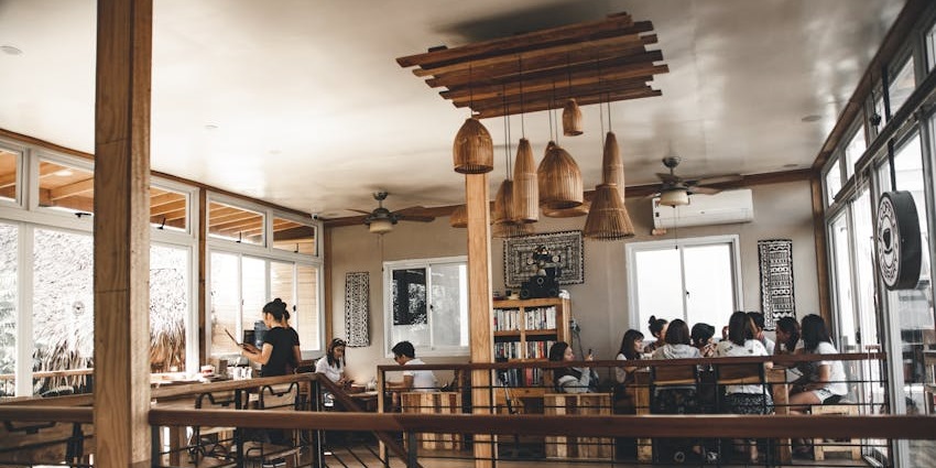 A busy cafe is shown with a two-story layout, many tables, and people sitting at them.