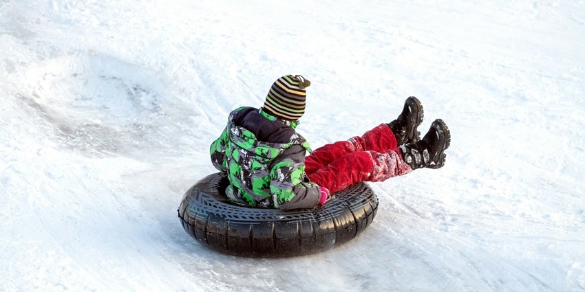 Adventurers sliding down slopes on snow tubes, enjoying snowfall in Himachal Pradesh.