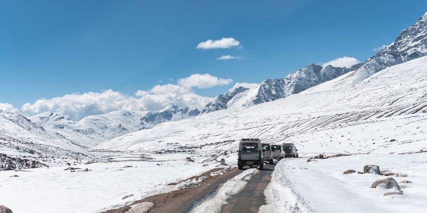 A breathtaking view of some cars driving down a snow covered road during the day.