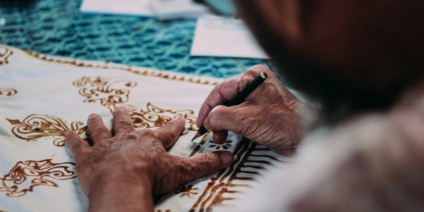 Image of man working on a garment with beautiful flower artworks