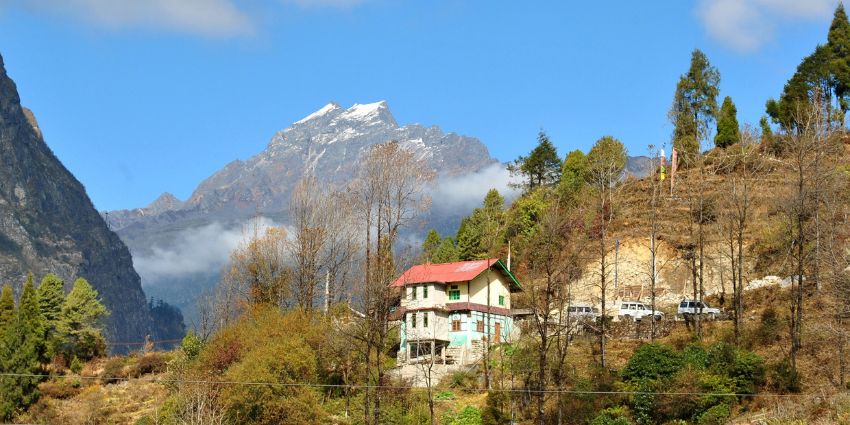 A panoramic view of a traditional wooden house against the backdrop of mountains, Lachung.
