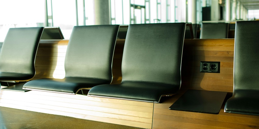 Spacious waiting area with rows of comfortable chairs inside a modern airport.
