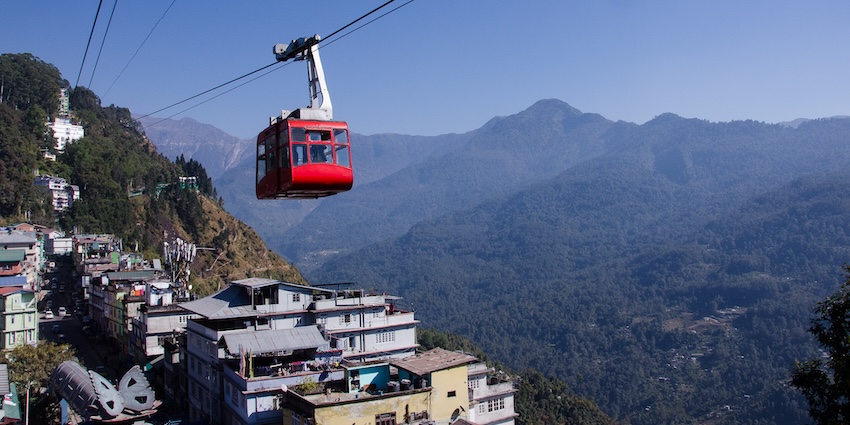 Red cable car of Gangtok Ropeway gliding above city buildings with snowfall in Gangtok.