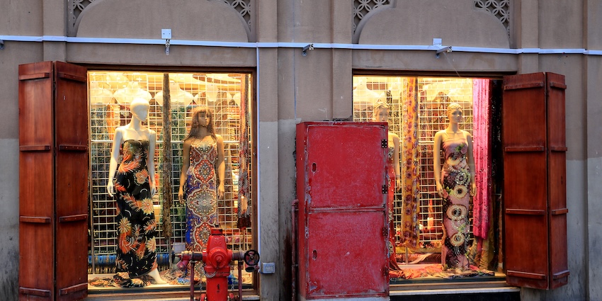 A colourful display of ready-made clothes, visible from the entrance of a shop.