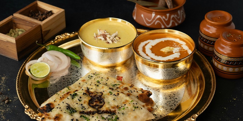 Traditional Indian thali with dal, naan, and assorted dishes served on a plate.

