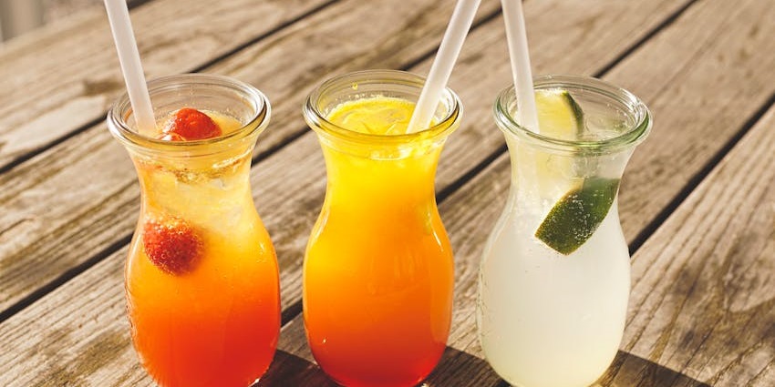Three assorted fruit juices in clear glasses at The Alchemy Grill and Lounge table setting.