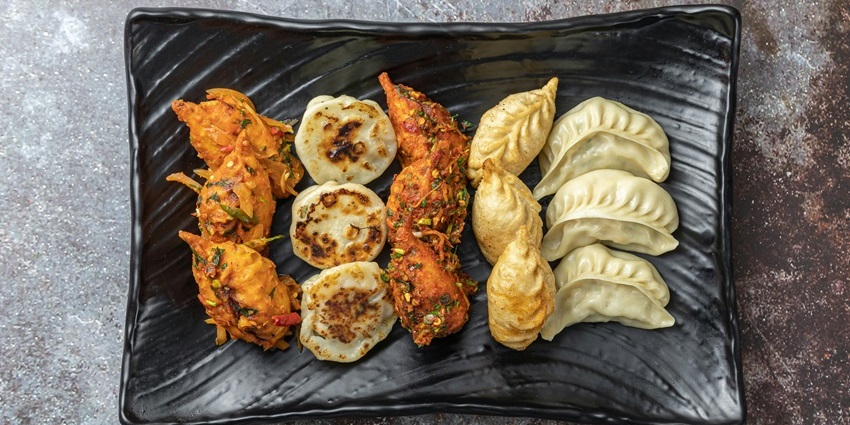 Momos platter served at The Cafe Lhasa with dipping sauces on a wooden table.