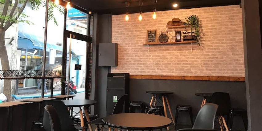 Cosy corner at The Coffee Shop with black tables, chairs, and an elegant decor.