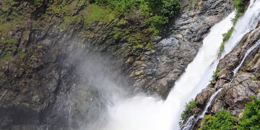 The powerful waterfall plunges down a sheer, dark rock face, creating heavy mist, one of the best among Tripura waterfalls.