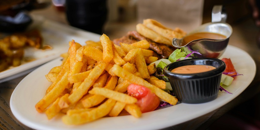 Crispy fries served with dipping sauce at The Greenhouse Café on a wooden table.