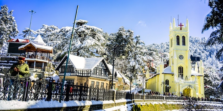 Snowfall in Shimla at The Ridge with snow-covered surroundings and distant hills.