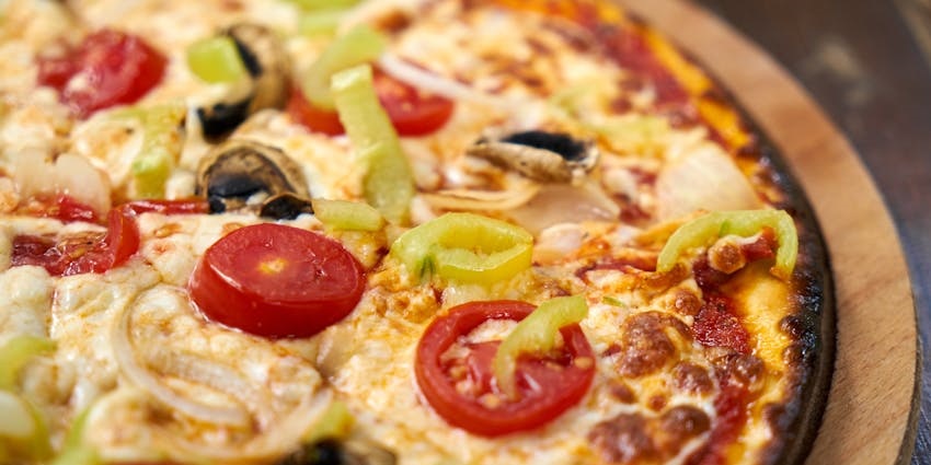 Pizza is placed on a circular plate and baked with a golden, cheesy crust at The View Restaurant & Lounge.