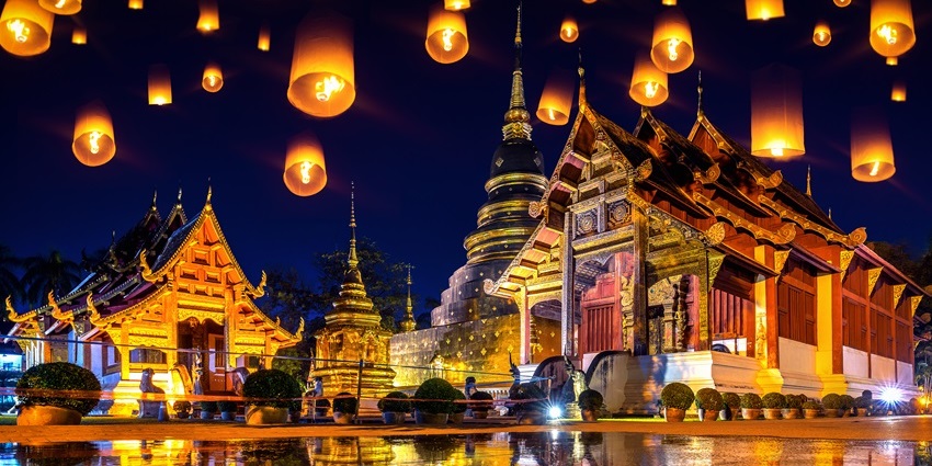 Sky lanterns glowing at night near Wat Phra Singh temple during Yi Peng Lantern Festival.