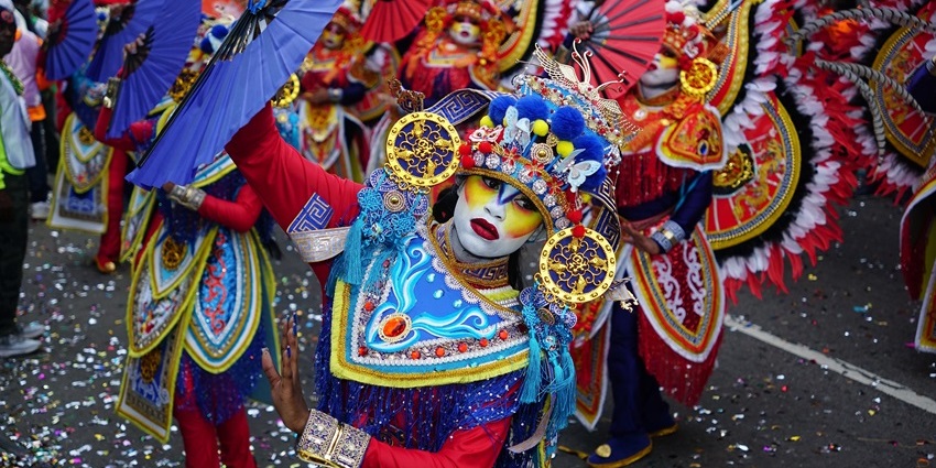Close-up image of a participant in a blue costume adorned with sequins and feathers.
