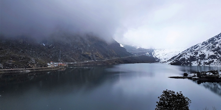 Serene Tsomgo Lake in East Sikkim surrounded by misty mountains with snowfall in Gangtok.