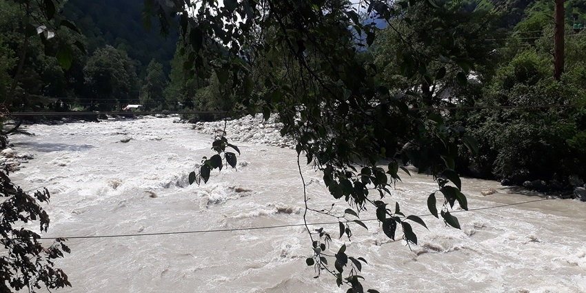 The Parvati River flows through lush green hills in Himachal Pradesh , showing snowfall in Kasol..