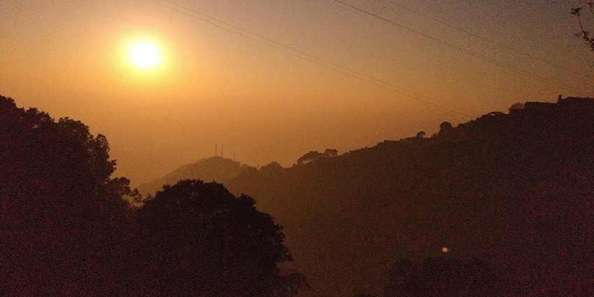 Silhouette of a person watching the glowing orange sunset over the calm ocean waves