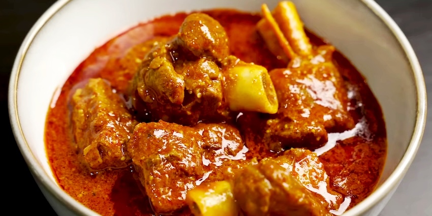 Close up of Rogan Josh, small lamb pieces with spicy gravy, served in a white dish bowl