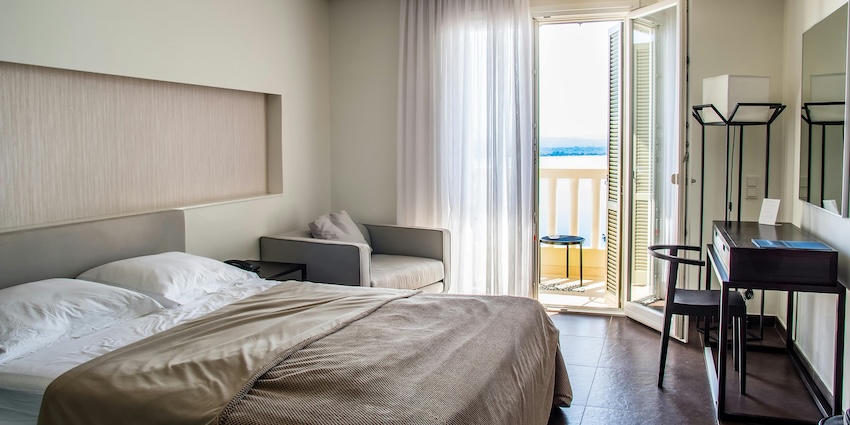 Historic hotel with green roof and alpine design set against rocky mountain peaks and blue sky